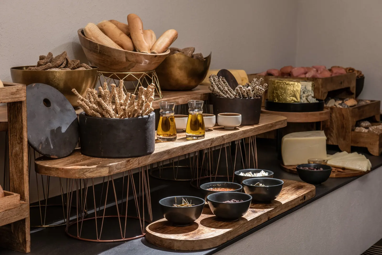 Breadsticks in black ceramics, olive oil carafes and dips on a wooden board