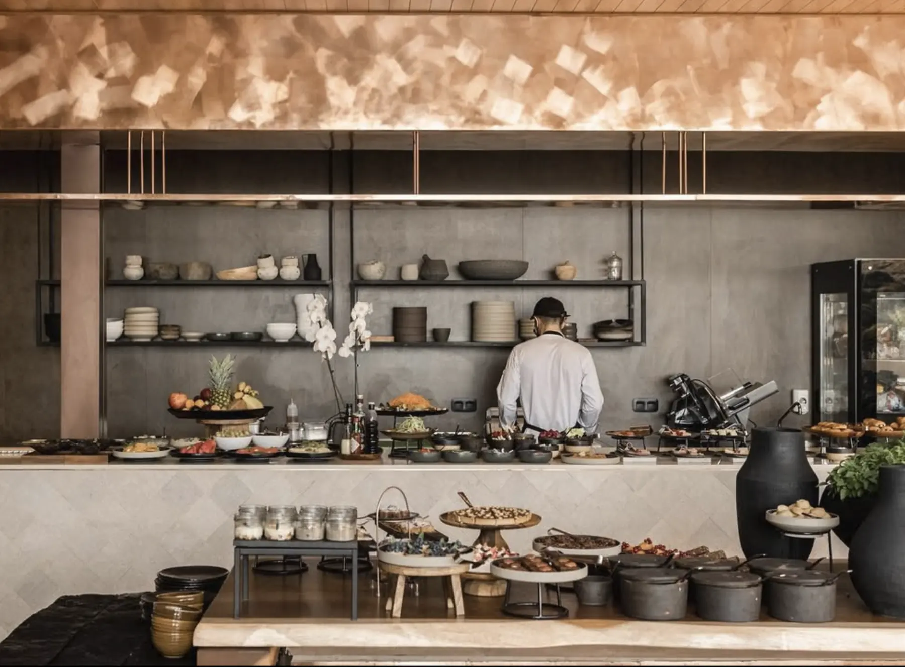 Breakfast buffet under a copper ceiling with ceramic shelves
