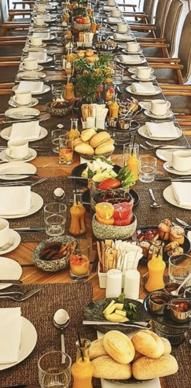 Long breakfast table for a group with rolls, fruit and juice