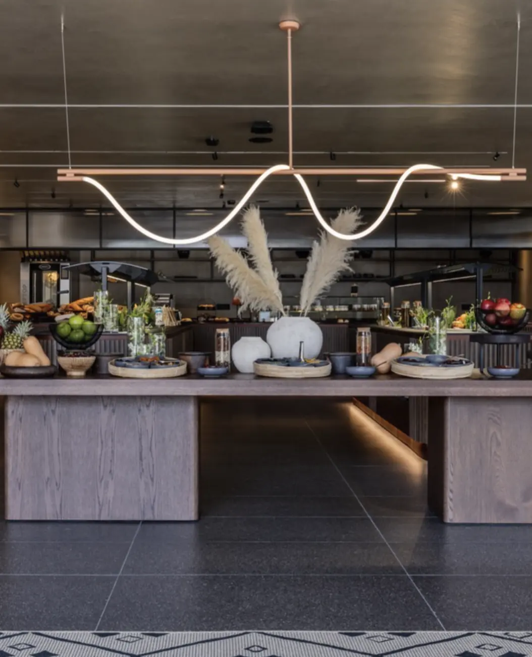 Buffet island with pampas grass under a wave-shaped light